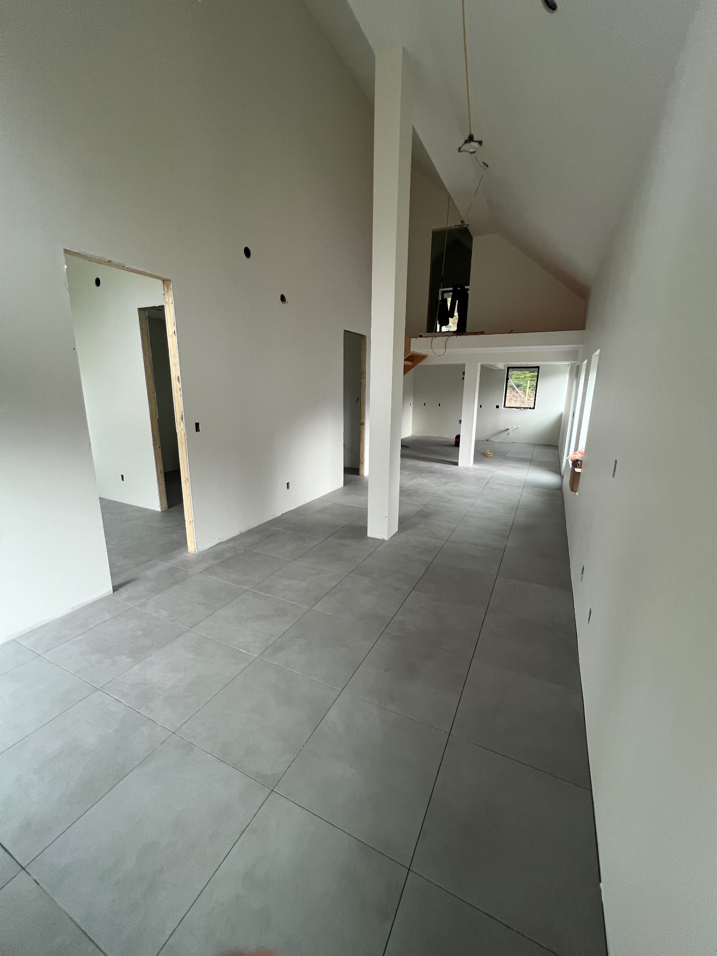 Open great room with large format grey porcelain floor tile and vaulted ceilings
