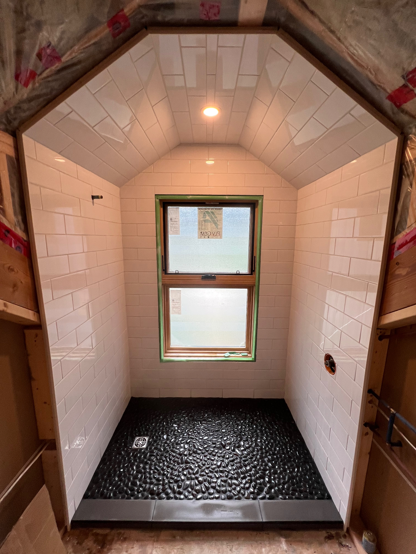 White subway tile shower with vaulted tiled ceiling and black pebble mosaic floor