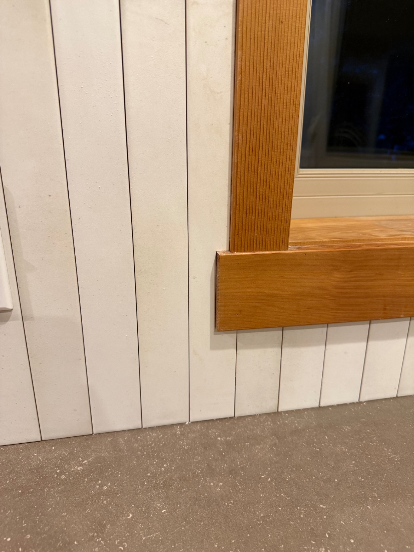 Shiplap-style white tile detail meeting cedar window trim