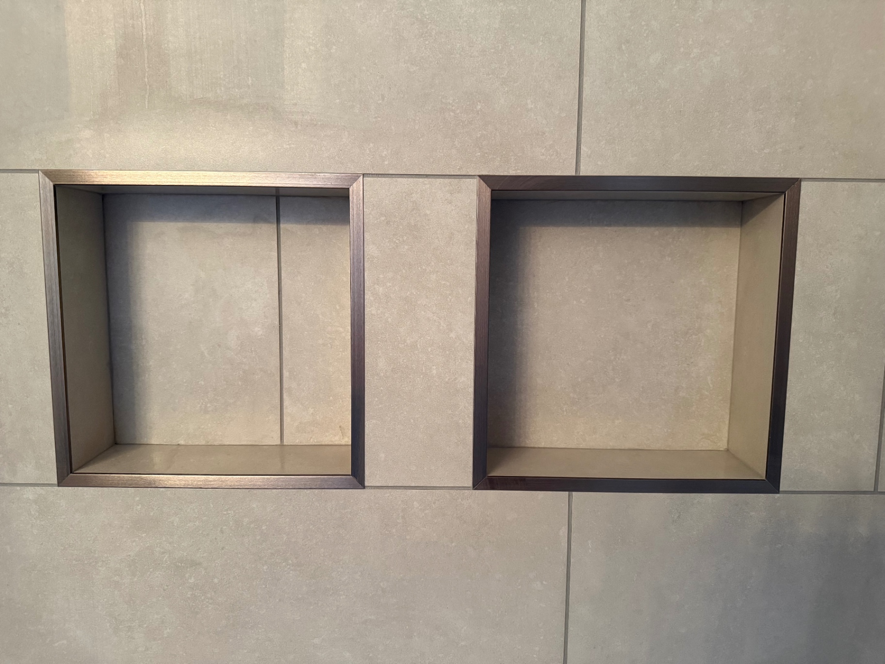Pair of recessed shower niches with bronze metal trim