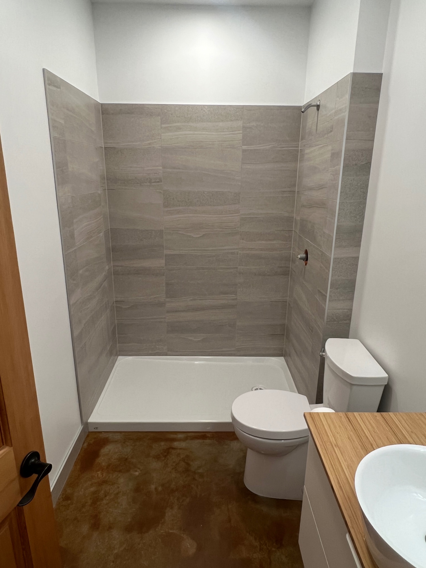 Stand-up shower with grey stone-look large format wall tile and white shower pan